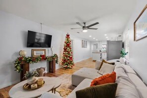 A modern living room with a flat-screen TV, a Christmas tree, and a ceiling fan. - Walk to free shuttle Nights of Lights !! (St. Augustine)