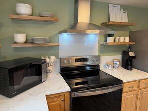 A modern kitchen with a built-in microwave, oven, and coffee maker.