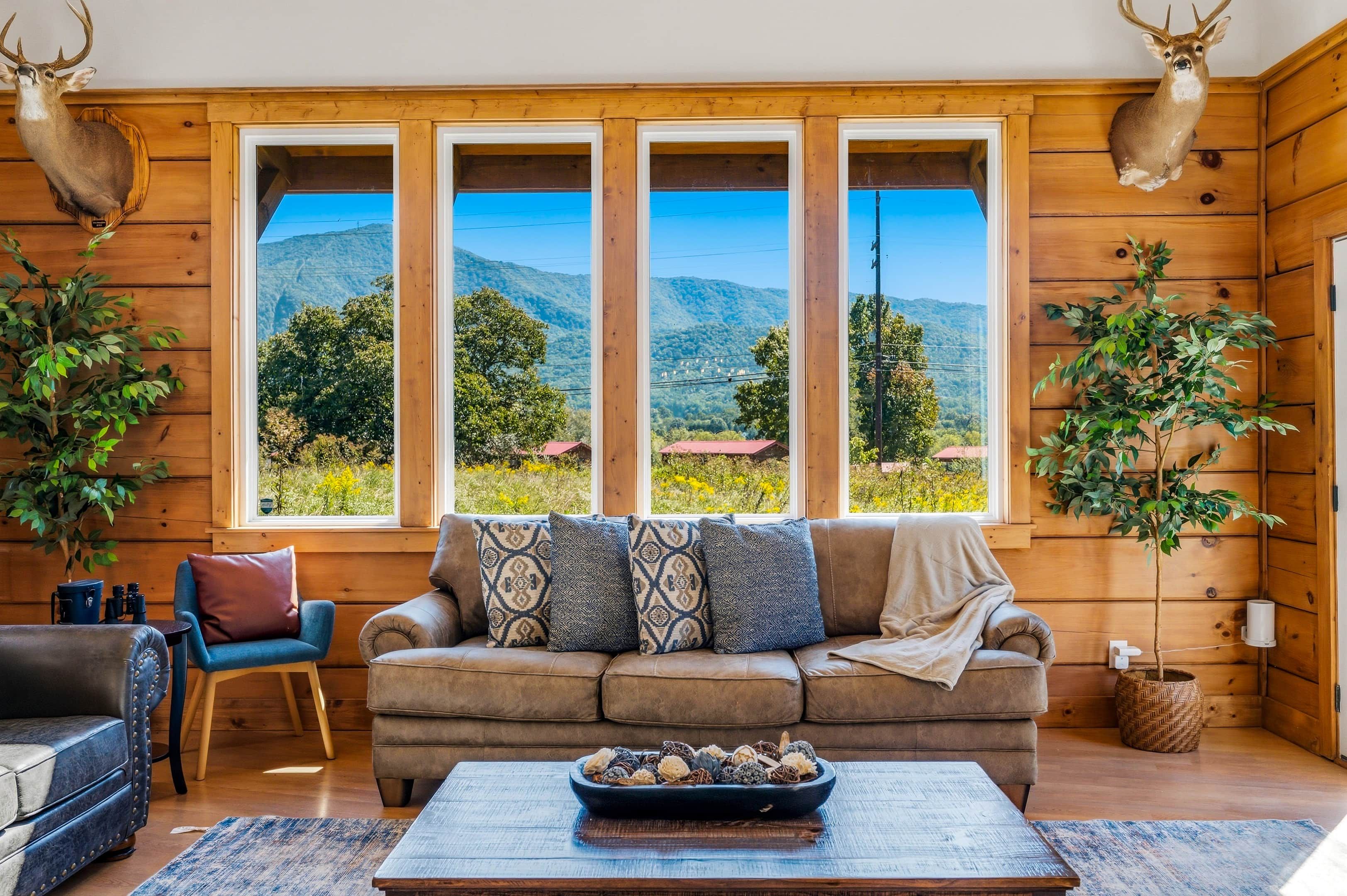 A cozy room with a large window, a sofa, a coffee table, and a plant.