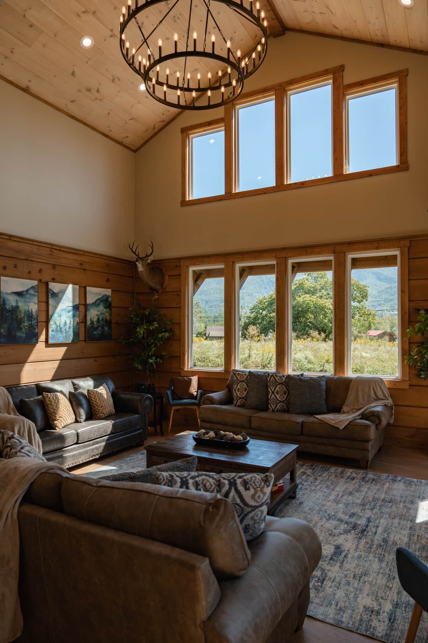 A spacious living room with high ceilings, large windows, and a chandelier.