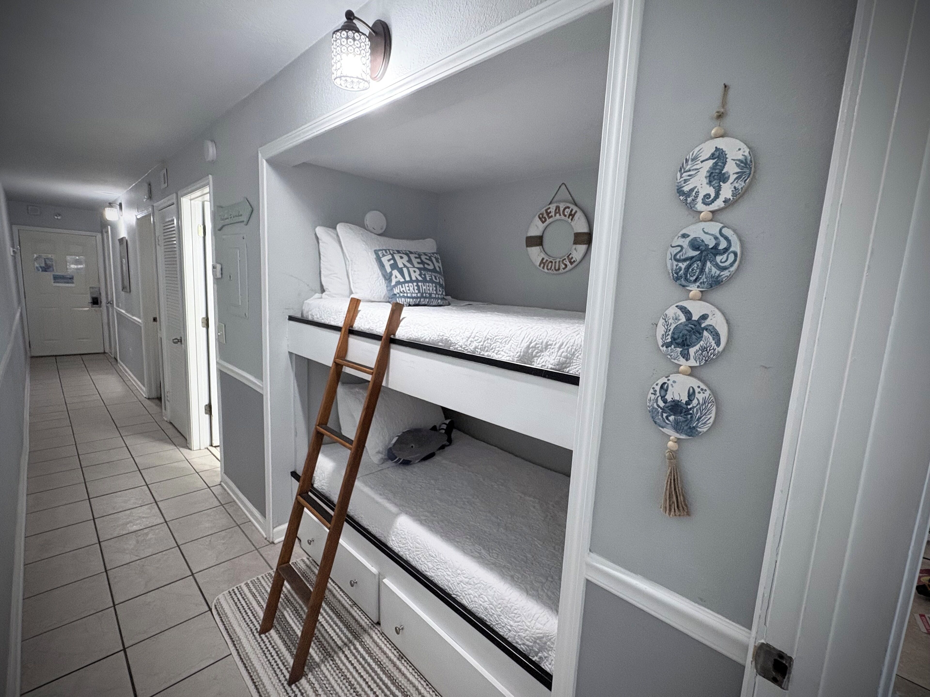 A bunk bed with a ladder, a wall clock, and decorative plates.