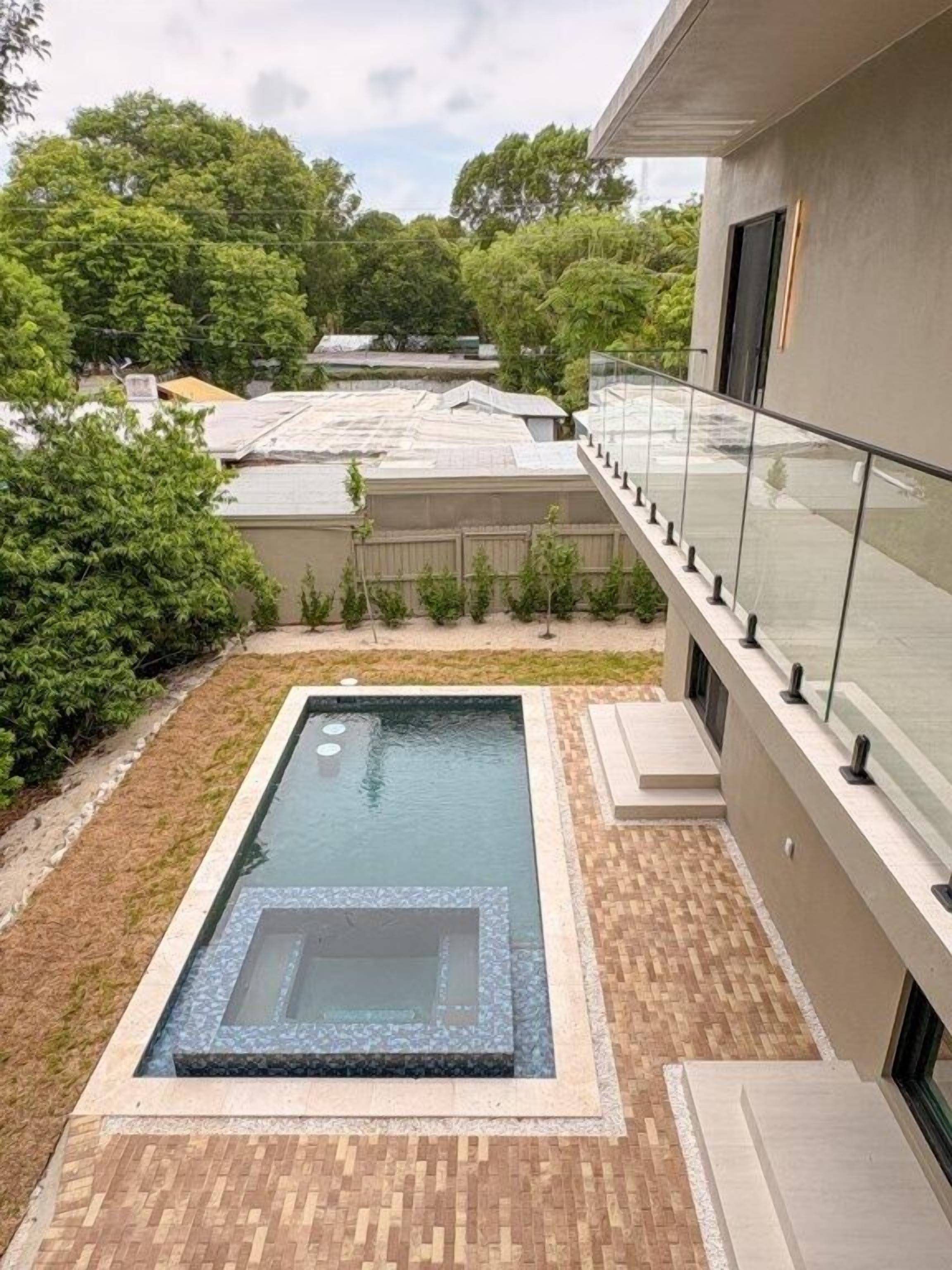 Ein Dachpool mit Glasgeländer, umgeben von einem angelegten Garten und einem modernen Gebäude.