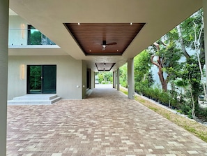 A covered walkway with a brick floor, leading to a building entrance. - Tropical, Large Modern Keys, New Island Mansion with a pool & 2 boat docks (Key Largo)