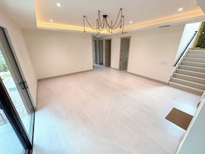 A spacious room with a modern chandelier, a staircase, and a view of the outdoors. - Tropical, Large Modern Keys, New Island Mansion with a pool & 2 boat docks (Key Largo)