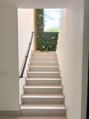 A staircase with a handrail leading to a landing with a view of greenery outside. - Tropical, Large Modern Keys, New Island Mansion with a pool & 2 boat docks (Key Largo)