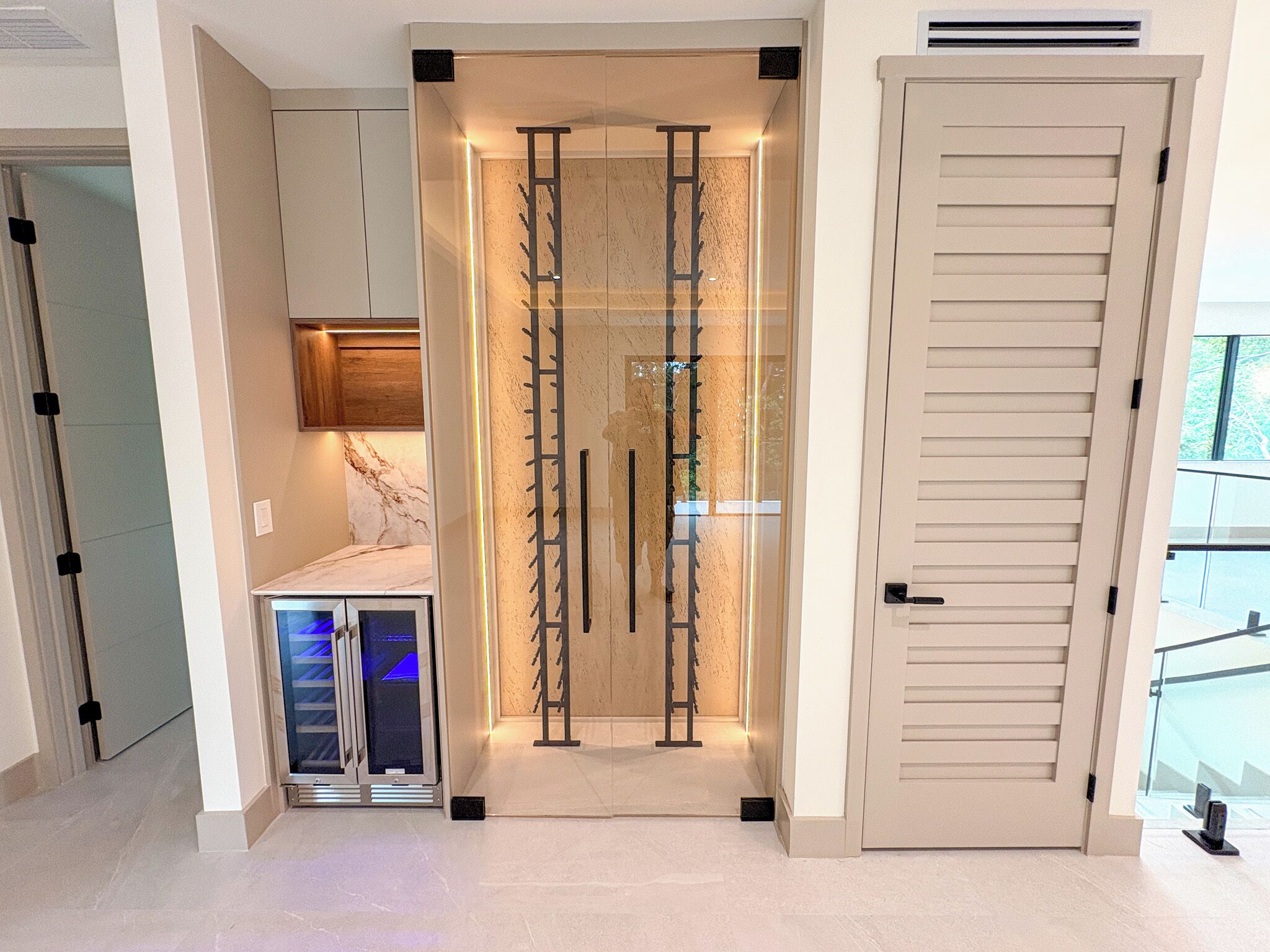 A modern interior with a glass door, a built-in refrigerator, and a sliding door.