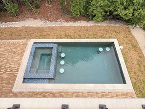 Ein rechteckiger Pool im Freien mit einer Fliesenbordüre und einer Ziegelumrandung.