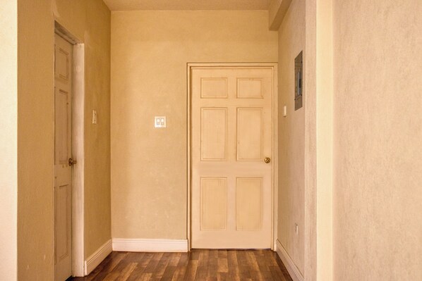 A hallway with a closed door, a light switch, and a small window.