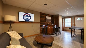 A furnished room with a sofa, a round table, a bar area with stools, and a sign for SVR Vacation Rentals.