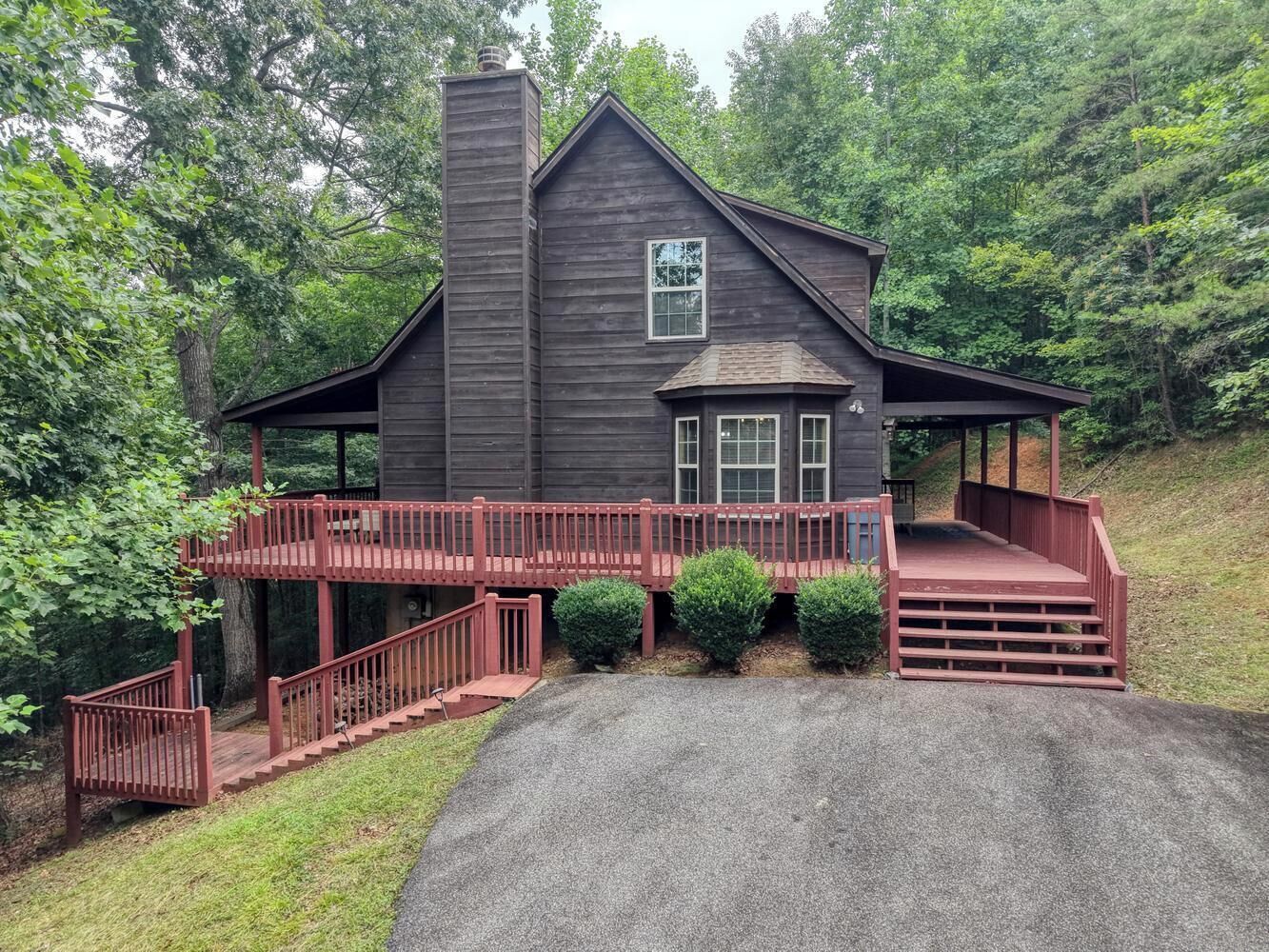 A two-story wooden house with a red staircase and a covered porch.