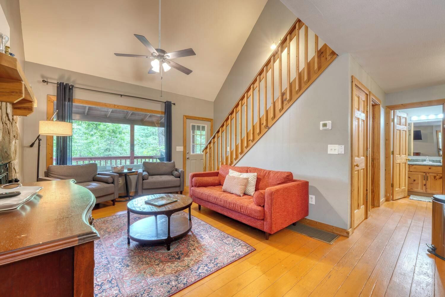 A spacious living room with a red sofa, a coffee table, and a ceiling fan.