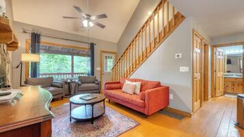 A spacious living room with a red sofa, a coffee table, and a ceiling fan.