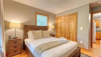 Ein Schlafzimmer mit einem Holzbett, Nachttischen, einem Holzschrank und einem Fenster mit Jalousien.