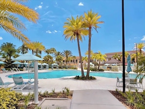 A pool area with lounge chairs, umbrellas, and palm trees. - Frozen & Jurassic Room | Theater | Pool & Spa 9120 (Kissimmee)