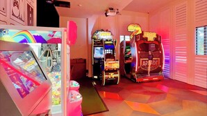 Ein Raum mit Spielautomaten, darunter ein Krabbenautomat und ein Spiel mit dem Thema 'Jurassic Park'.