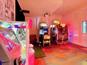 Ein Raum mit Spielautomaten, darunter ein Krabbenautomat und ein Spiel mit dem Thema 'Jurassic Park'.