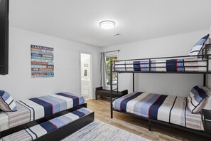 Habitación tipo dormitorio con literas, un televisor montado en la pared y un cartel motivacional.