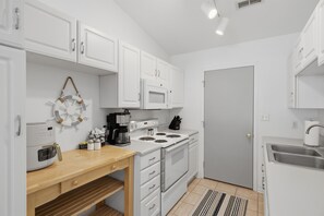 A compact kitchen with white cabinets, a microwave, a stove, a coffee maker, and a small sink. - Waterfront|Sleeps10|GameRoom|Covered Patio|PetsOk (Lake Ozark)