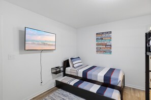 A bedroom with a bed, a TV mounted on the wall, and a poster with various activities. - Waterfront|Sleeps10|GameRoom|Covered Patio|PetsOk (Lake Ozark)