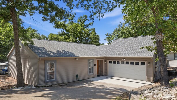 Ein Bungalow mit Garage, Eingangstür und Auffahrt.