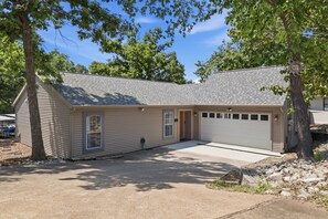 Ein Bungalow mit Garage, Eingangstür und Auffahrt.