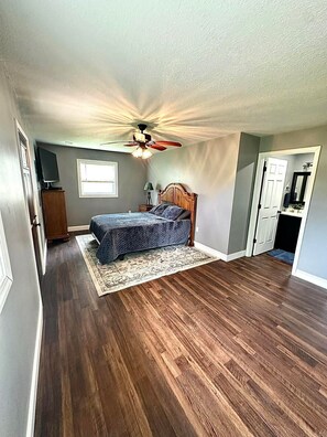 A bedroom with a bed, a ceiling fan, a nightstand, and a dresser.