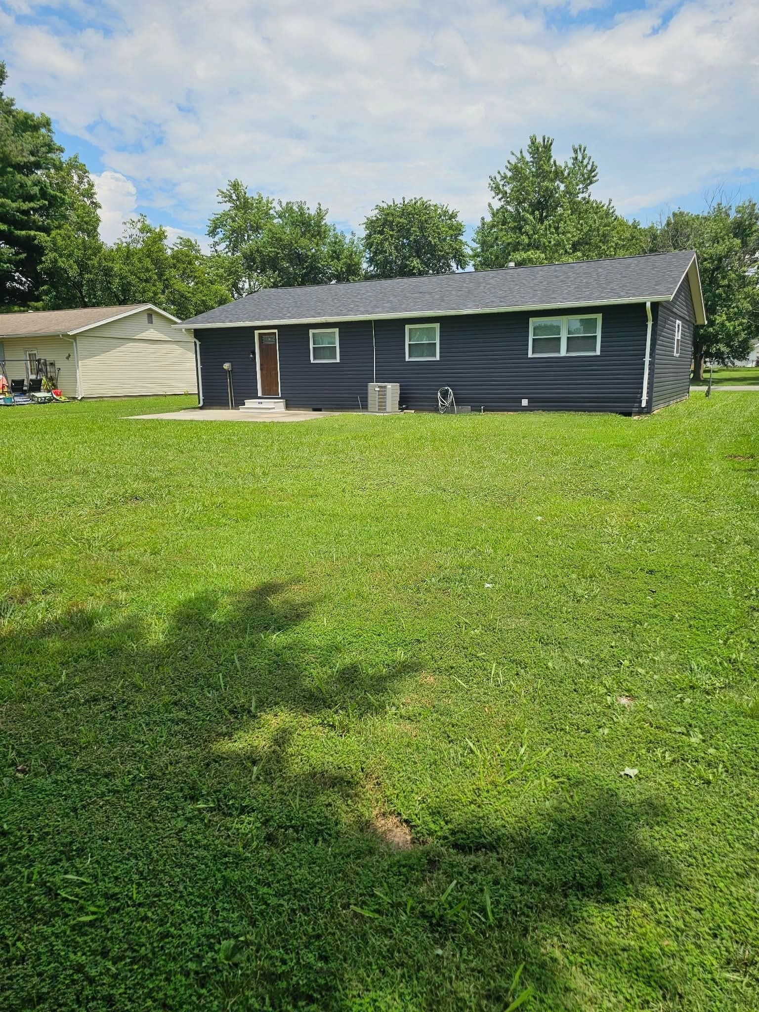 A single-story house with a dark exterior, a front porch, and a well-maintained lawn.
