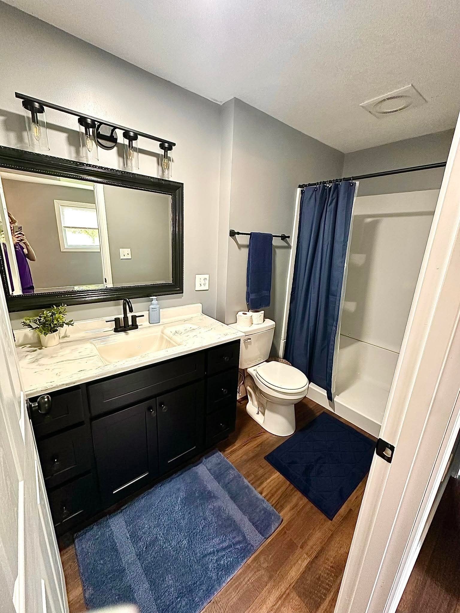 Une salle de bain équipée d’un lavabo, d’un miroir, de toilettes et d’une douche.