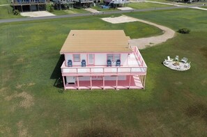 A single-story building with a flat roof, a covered porch with multiple chairs, and a circular seating area with a fire pit. - Cozy 2br/2b Surfside beach escape with a fun downstairs game room near the Gulf (Surfside Beach)