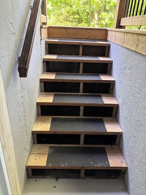 Un escalier en bois avec des marches grillagées menant à un espace extérieur.