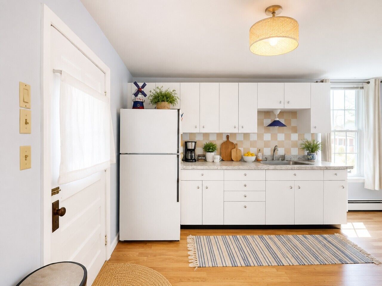 A kitchen with white cabinetry, a refrigerator, a coffee maker, and a hanging light fixture.