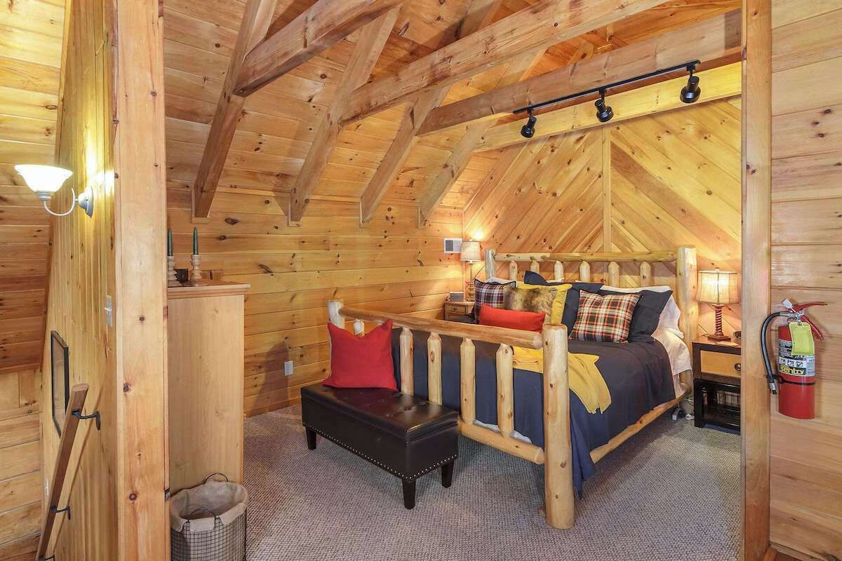 Une chambre confortable dans un chalet en bois, avec un lit en mezzanine, un banc et un extincteur.