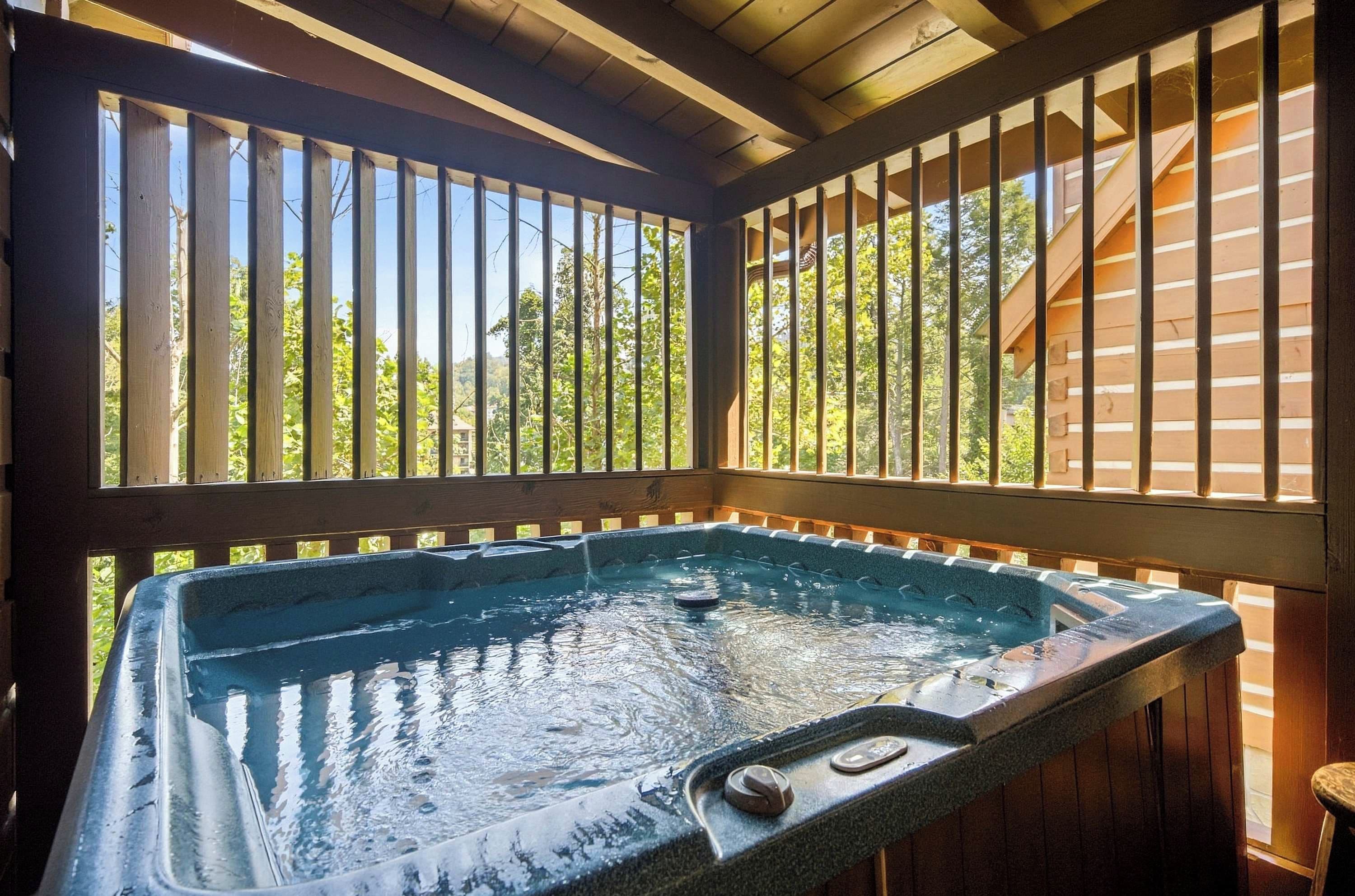 A hot tub with a wooden deck and railings, surrounded by trees.