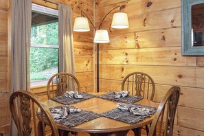 A wooden dining room with a round table, four chairs, and a floor lamp.