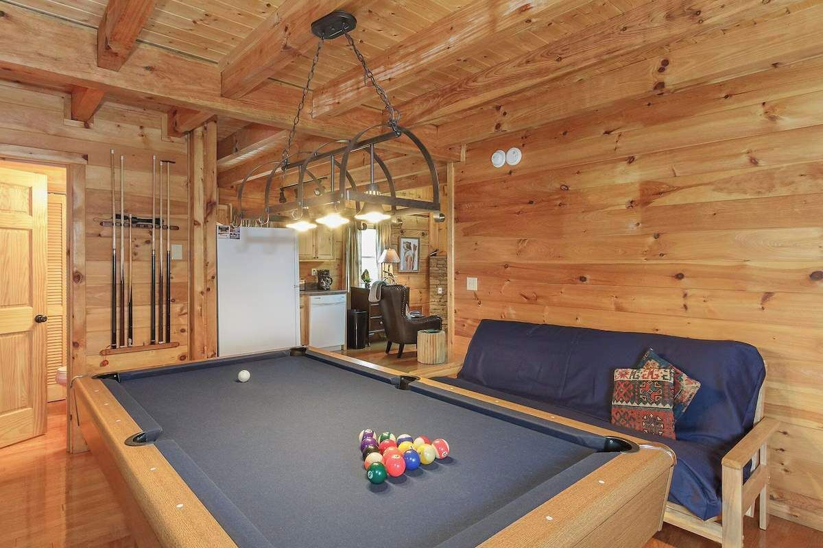 Ein Billardtisch mit Kugeln, eine Couch und eine Holzbalkendecke.