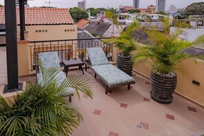 Eine Dachterrasse mit Liegestühlen, einem kleinen Tisch und Topfpflanzen.
