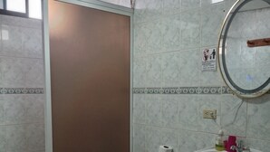 Un baño con inodoro, lavamanos y un cubo de basura verde.