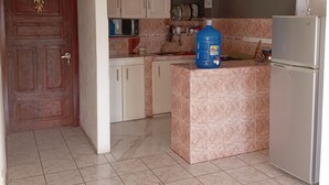 Una cocina con una puerta marcada '2', armarios, microondas, dispensador de agua y refrigerador.