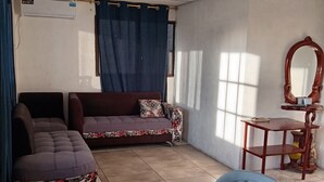 Una habitación con sofá modular, una mesita y un espejo.