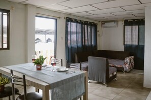 Zona pranzo con tavolo, sedie, una pianta in vaso e un bicchiere di vino rosso.