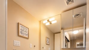 A modern bathroom with a toilet, sink, and mirror. There are two framed motivational quotes on the wall.