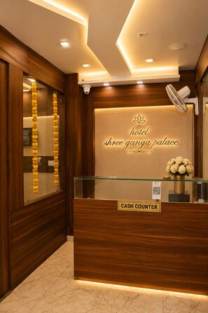 A hotel reception desk with a cash counter, a sign reading 'hotel shree ganga palace', and a security camera. - HOTEL SHREE GANGA PALACE (Gwalior)