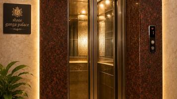 An elevator with a marble wall and a sign indicating 'Shree Ganga Palace.'