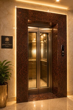 An elevator with a marble wall and a sign indicating 'Shree Ganga Palace.'