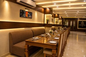A long dining table set with chairs, a cushioned bench, and a wall-mounted air conditioner.