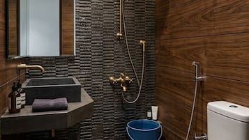 A modern bathroom with a stone wall, wooden paneling, a sink, a toilet, and a shower.