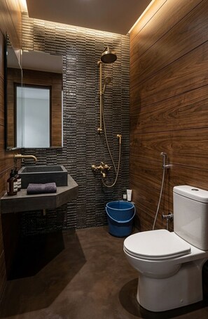 A modern bathroom with a stone wall, wooden paneling, a sink, a toilet, and a shower.
