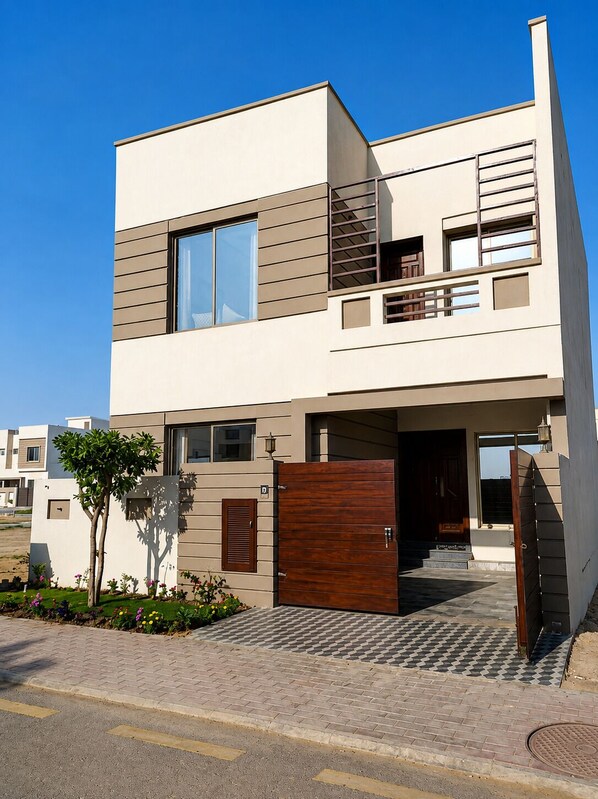 A modern two-story residential building with a flat roof, large windows, and a gated entrance.