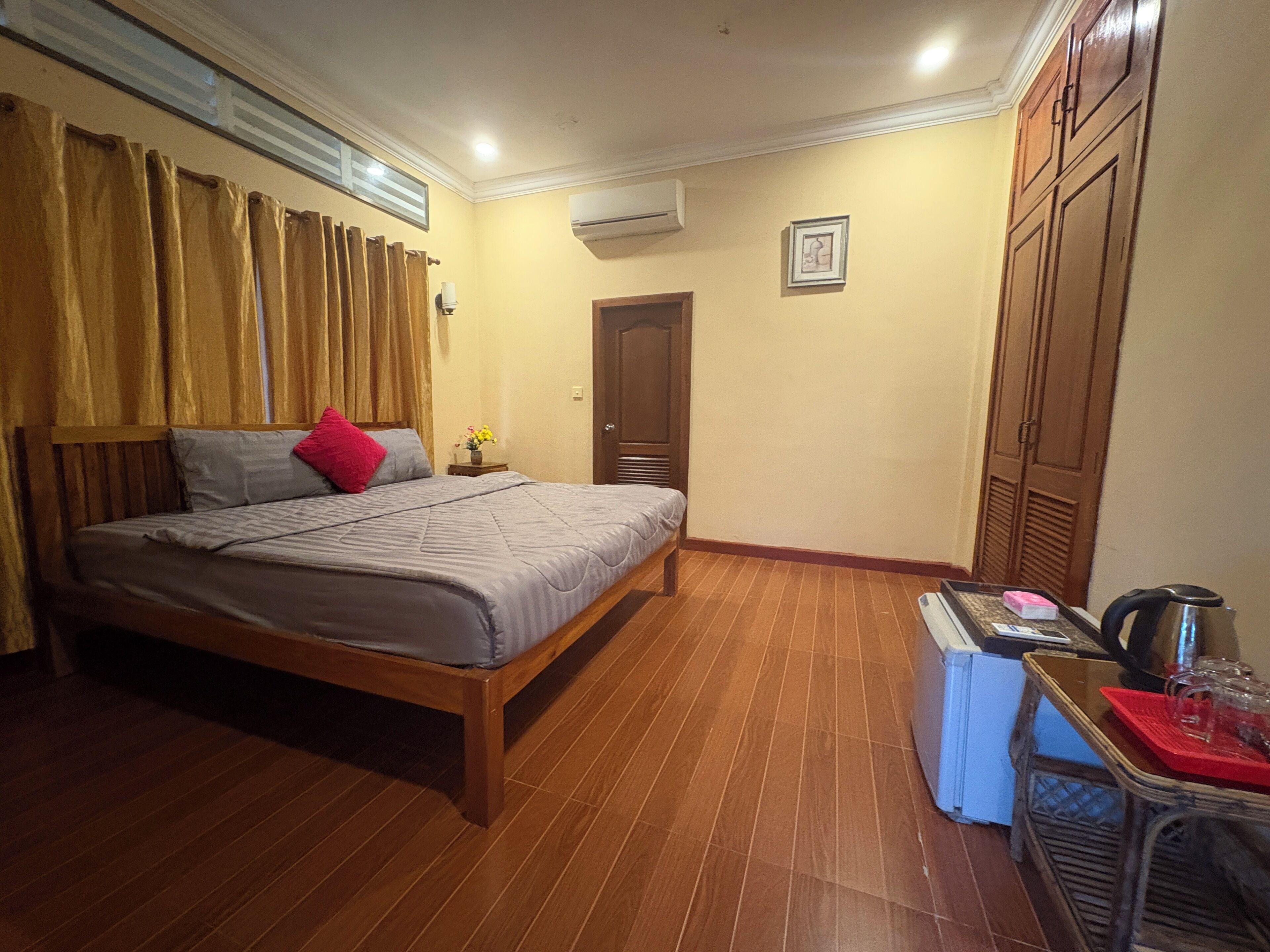 Une chambre à coucher comprenant un lit, une table de chevet, une table avec une bouilloire et une armoire.