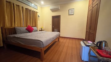 Une chambre à coucher comprenant un lit, une table de chevet, une table avec une bouilloire et une armoire.